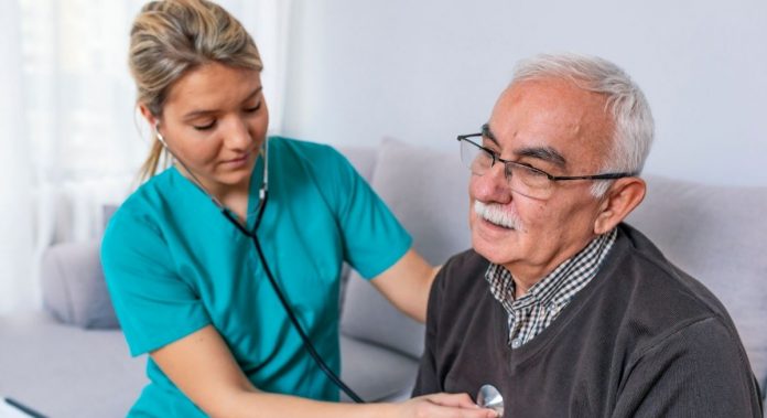 Krankenschwester hört älteren Patienten mit Stethoskop ab, Credit: Canva